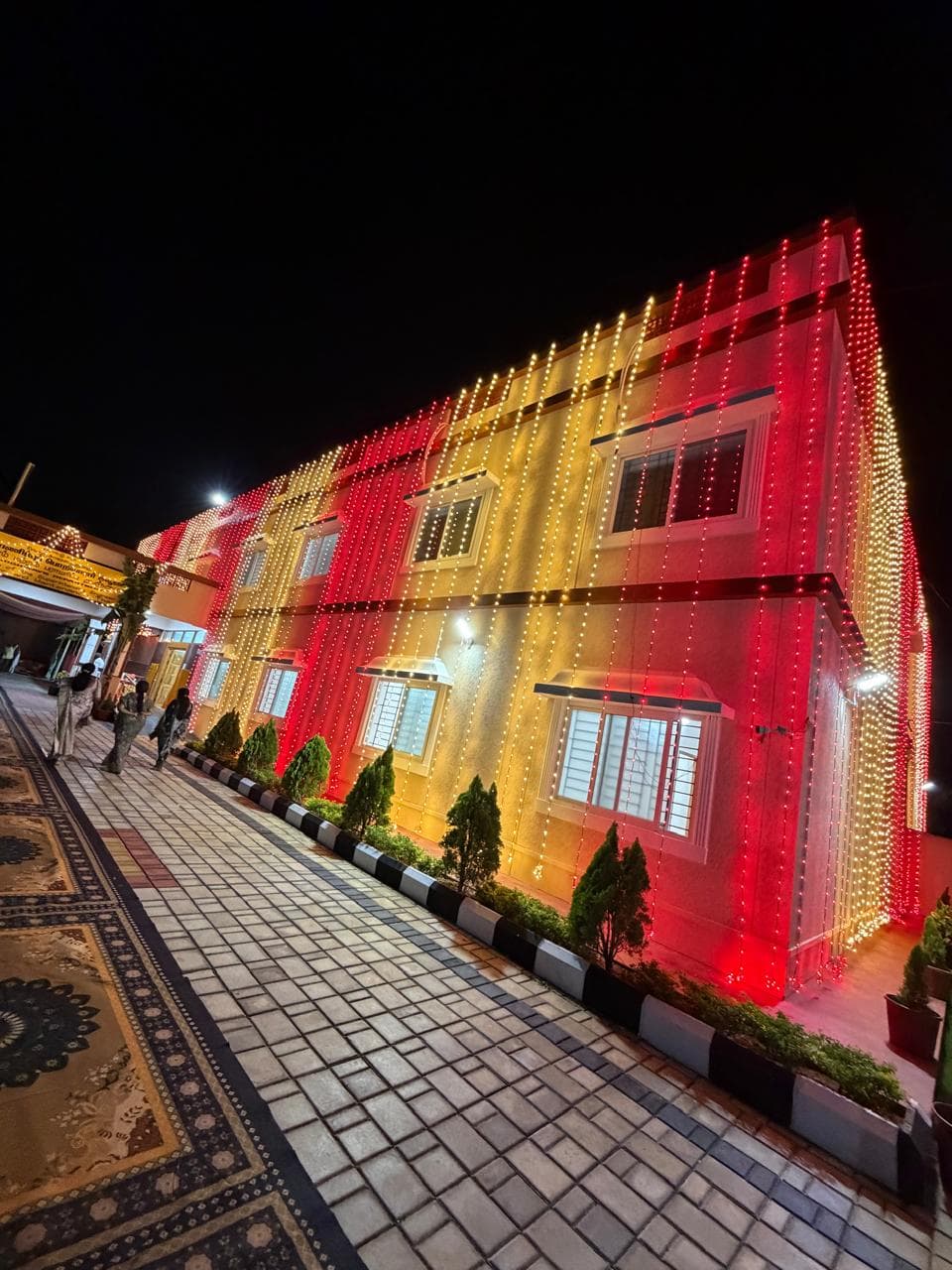 The Highway Department office block lit at night with a paved entrance walkway and planted borders.