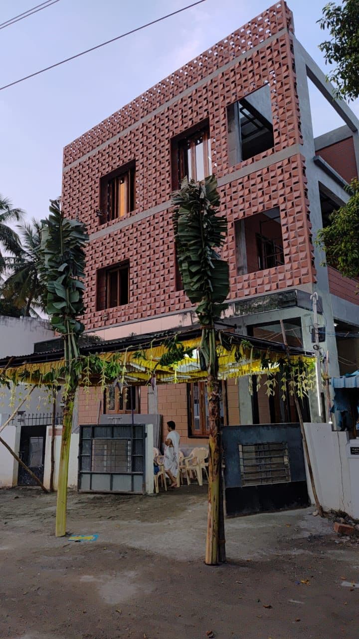 Street view of the exposed-brick residence in Thanjavur with its perforated brick screen and boundary wall.