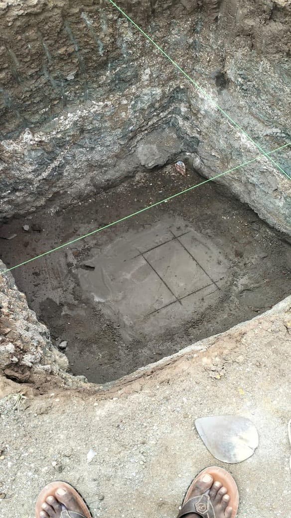 An excavated pad footing with the blinding layer poured and setting-out lines strung across the pit.